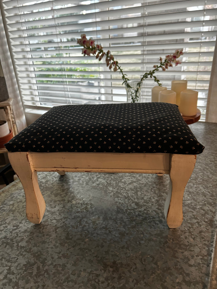 Accent stool in progress, shown before refinishing with a black painted frame and green zebra-patterned upholstery